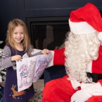 Little girl shows her coloring pages to Santa